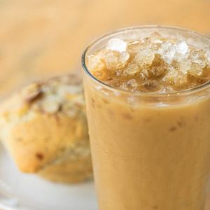 iced coffee in a pint glass, sitting beside a muffin